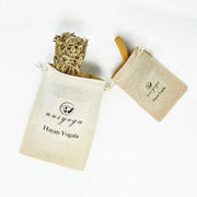 İki bez çantada yer alan kurutulmuş bitki ve tahta çubuk görüntüsü.