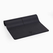 Siyah renkli yoga matı yarı rulo halinde yerde duruyor.